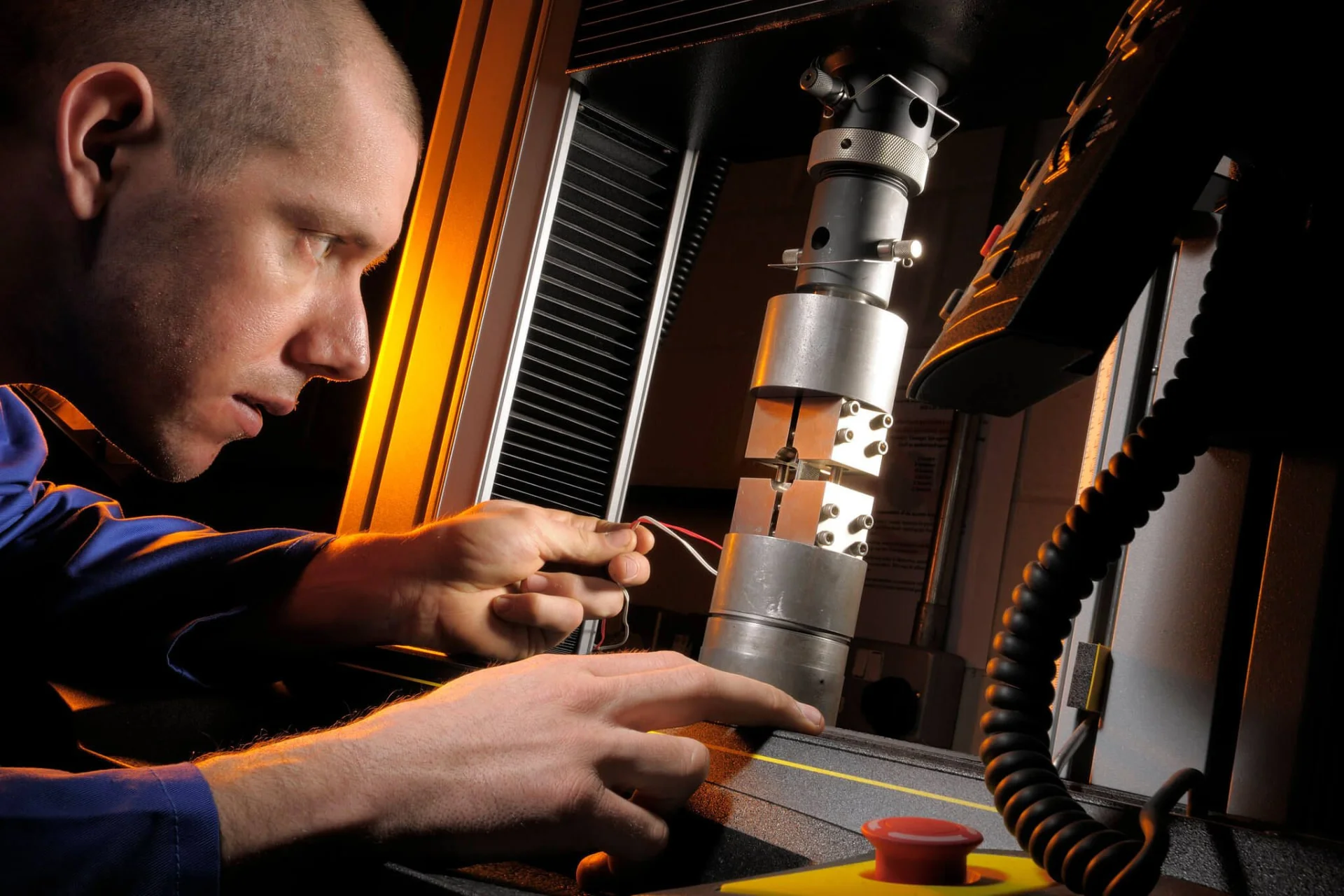 Technician testing a metal sample in a materials testing rig